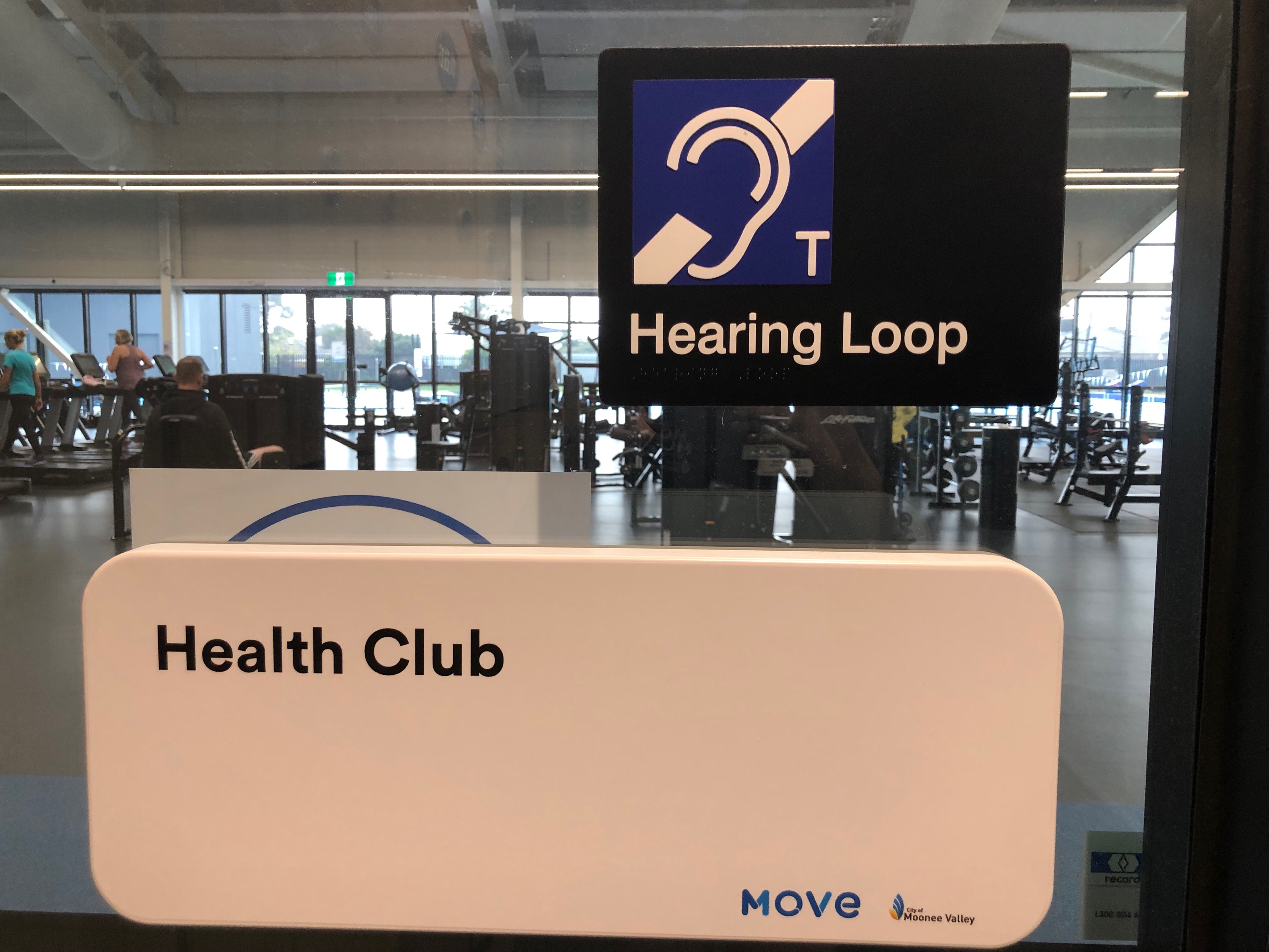 Image of health club entrance door with Hearing Loop signage
